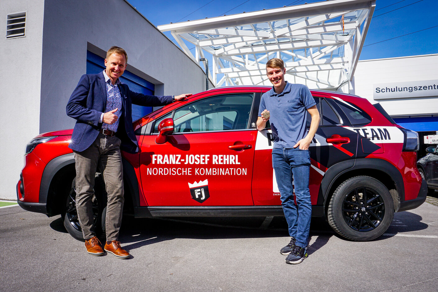 Roland Pfeiffenberger, Managing Director SUZUKI AUSTRIA, freut sich mit Franz Josef Rehrl über dessen Medaille und den neuen S-CROSS HYBRID.